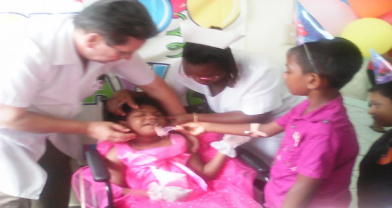 Little Sherlana Plass takes a bit of her birthday cake from a fellow patient as Dr Ronaldo Medina Dominquez and a nurse look on.