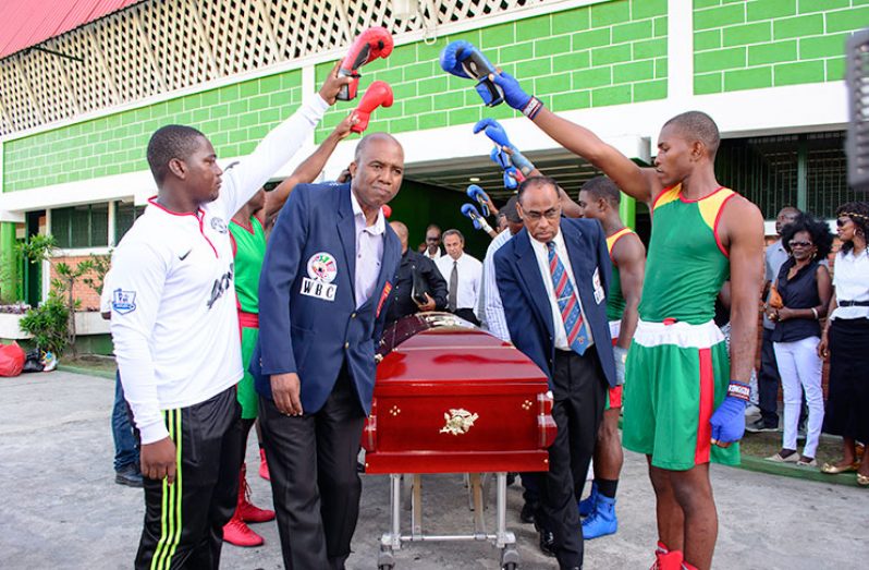 Members of the Guyana Defence Force Boxing Gym give Maurice Boyce a glove of Honour as GBBC’s secretary Trevor Arno (second left) and Treasurer Andrew Thorne (second  right) bears the coffin with the remains of Boyce yesterday at the Cliff Anderson Sports Hall (Samuel Maughn photo).