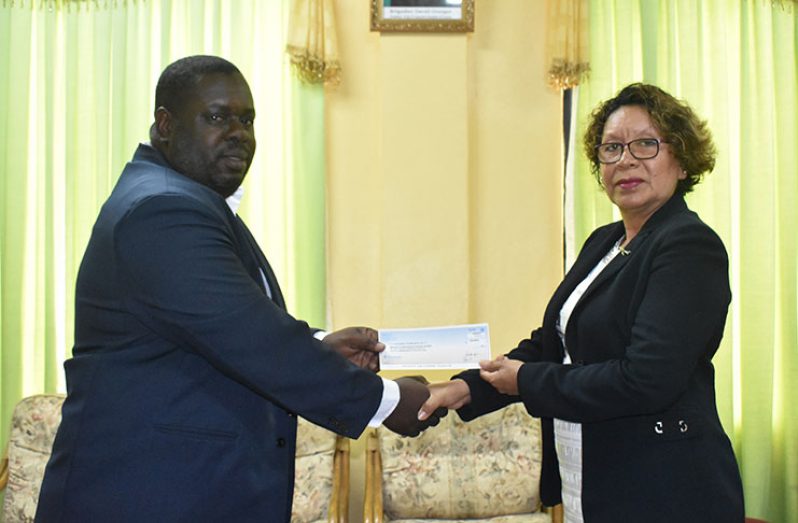 Guyana Goldfields Field Assistant Leon Roberts hands over the cheque to Minister within the Ministry of Indigenous Peoples’ Affairs, Valerie Garrido-Lowe