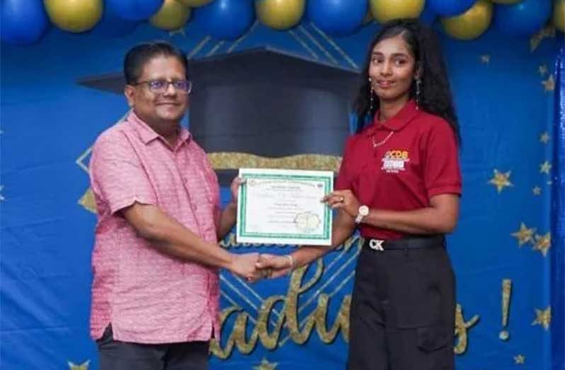 Finance Minister Dr. Ashni Singh hands over a certificate to one of the graduates