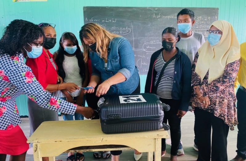 Education Minister, Priya Manickchand handing over the suitcase of cash to several teachers and parents at the Cotton Field Secondary. Also pictured is Regional Education Officer, Nichola Matthews (left) (File photo)