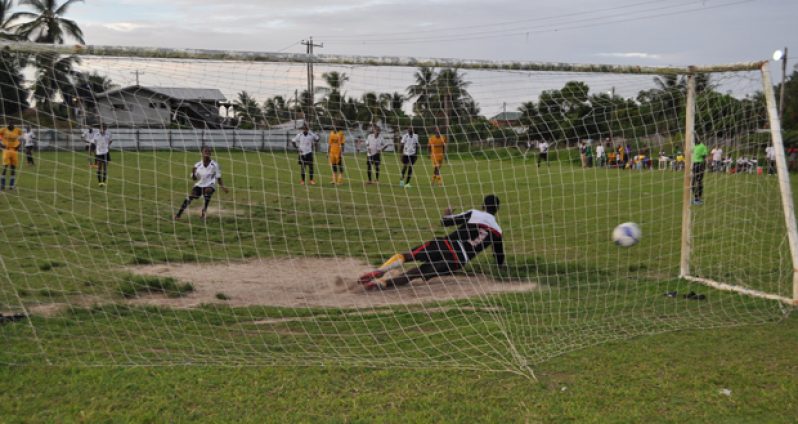 Agricola Red Triangle’s Gordon Grant scores from the penalty spot against Javier Greene