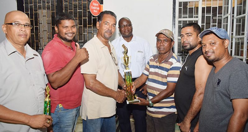 Sponsor Soomdat Jeet (right) hands over the winning trophy to Brian Allen in the presence of other members of the victorious team. (Cullen Bess-Nelson photo)