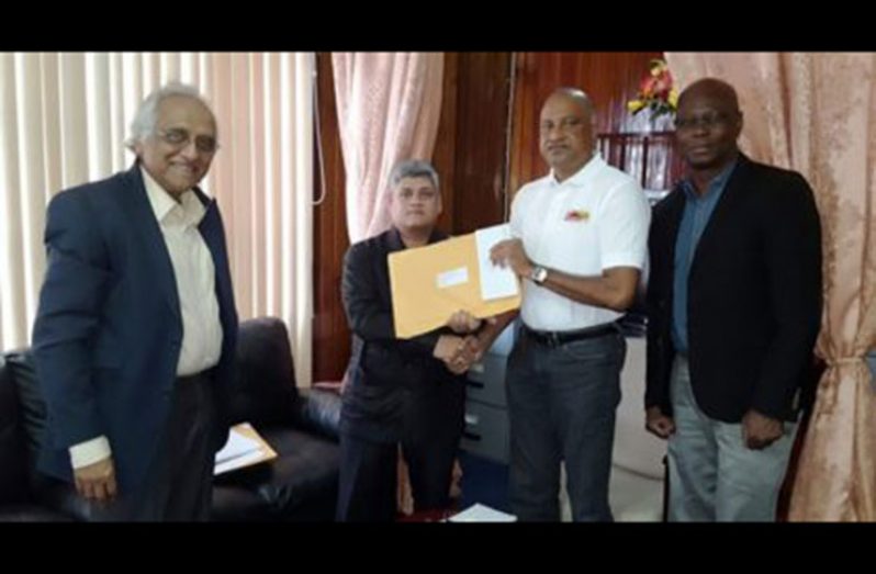 Junior Finance Minister Jaipaul Sharma handing over the reports to Police Commissioner Seelall Persaud in the presence of Sydney James, Assistant Police Commissioner and Head of the Special Organized Crime Unit (SOCU), and Christopher Ram and John Barnes, forensic auditors