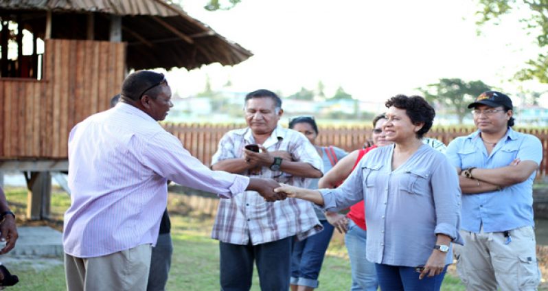 Minister Valerie Garrido-Lowe gives contractor Colin Andrews a ceremonious handshake for delivering the spanking new village