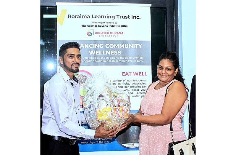 Representative of the Ministry of Health, Dr. Michael Perreira, presents the winner of the health challenge, Turandia Cathrupaul, with her gift hamper