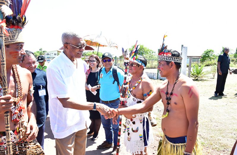 President David Granger greets a resident of St. Ignatius upon his arrival at the village for the Rupununi Heritage celebrations 2018. Also in photograph are Chairman of the National Toshaos' Council, Nicholas Fredericks (left); and Brazilian Vice-Consul, Ms. Lisa Mary Sousa Dos Reis.