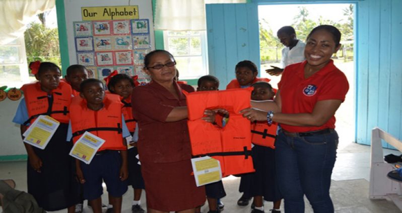 Akosua Mc Pherson Public, Communications Officer of the Maritime Administration Department, handing over life jackets to Head Mistress Faye Hicks of Holy Name Primary School 