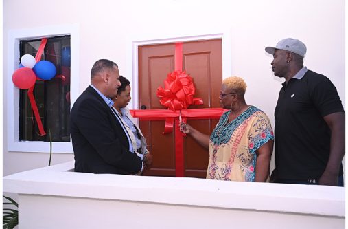 One of the beneficiaries of the Housing Ministry’s Adequate Housing and Urban Accessibility Programme cutting the ribbon to her new house. Pictured are Minister of Housing, Hon. Collin Croal and Minister within the Ministry, Hon. Vanessa Benn