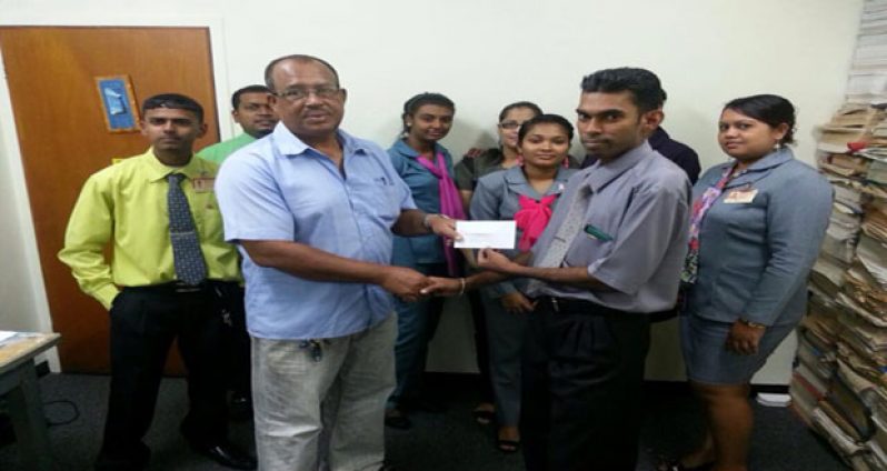 Bryan Baker of NBS (New Amsterdam) hands over sponsorship cheque to Hubern Evans in the presence of other staff members.