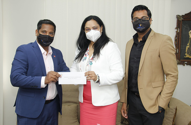 Minister of Human Services and Social Security, Dr. Vindhya Persaud, being presented with the cheque by Abbas Hamid, a Director of Vitality Inc. Also in photo is Director of Social Rank Media, Dr. Rosh Khan