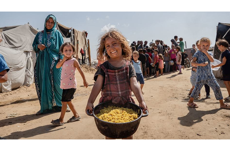 A young girl carries a pot of cooked food in Al-Mawasi, Gaza (WFP/Maxime Le Lijour)