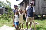 A family stands outside their home damaged by Hurricane Beryl in St. Andrews, Grenada (UNICEF/Sam Ogilvie photo)