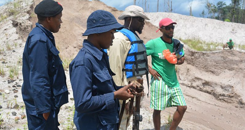 Law-enforcement officers and Senior Mines Officer Josiah engage the owner of a mining operation about safety concerns on Monday