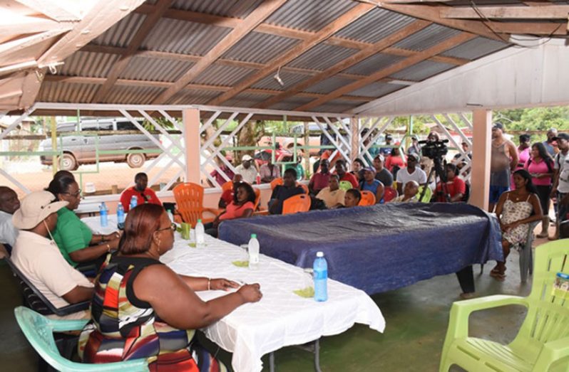 Minister of Citizenship  Winston Felix and Minister in the Ministry of Natural resources, Simona Broomes, speak with miners and members of the business community at Puruni landing Monday. (Kawise Wishart photo)