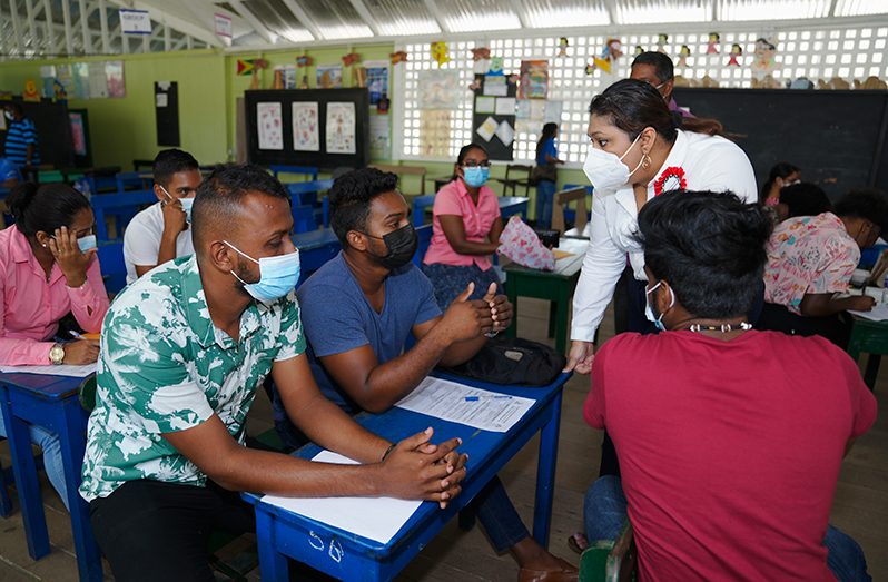 Education Minister Priya Manickchand assisting a group of young men with their applications