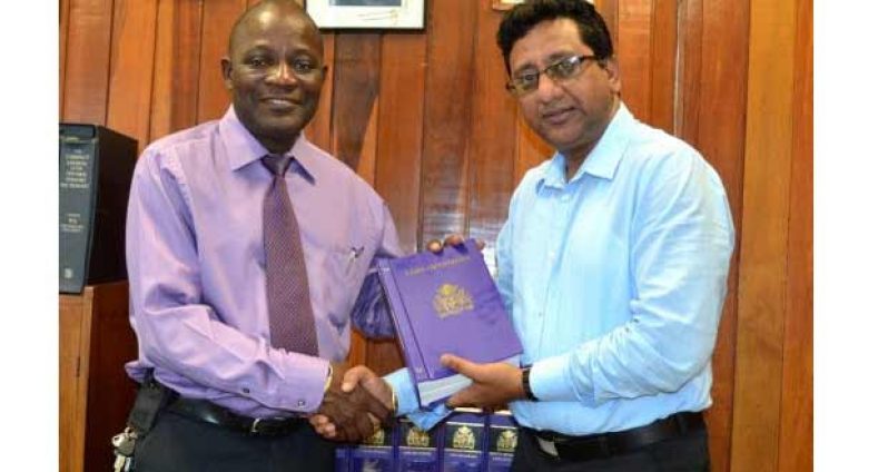 Minister of Legal Affairs and Attorney General, Anil Nandlall hands over a copy of the books to Jacob Opadeyi, Vice Chancellor of the University of Guyana