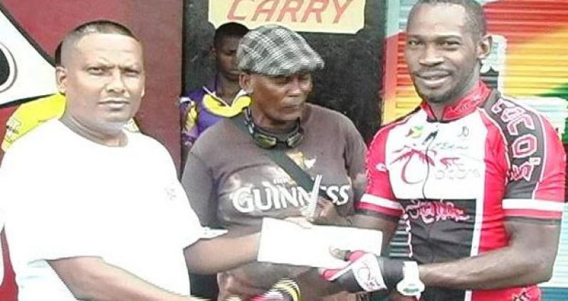 Banks DIH Berbice Sales Supervisor, Jagnarine  Persaud,  presents cash prize to Junior Niles..