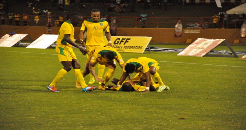 Guyana’s Pernell Schultz (on the ground) is swarmed by Walter Moore (right), (L-R) Joshua Brown, Neil Danns and Matthew Briggs after scoring his second goal of the game. (Delano Williams photos)