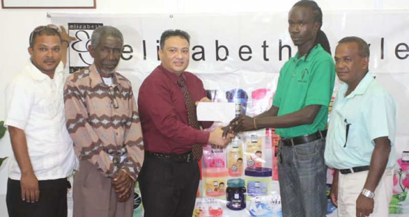 Vice-preisdent of the Berbice Cricket Board receives the sponsorship cheque from Bissoondyal Singh in the presence of other representatives.