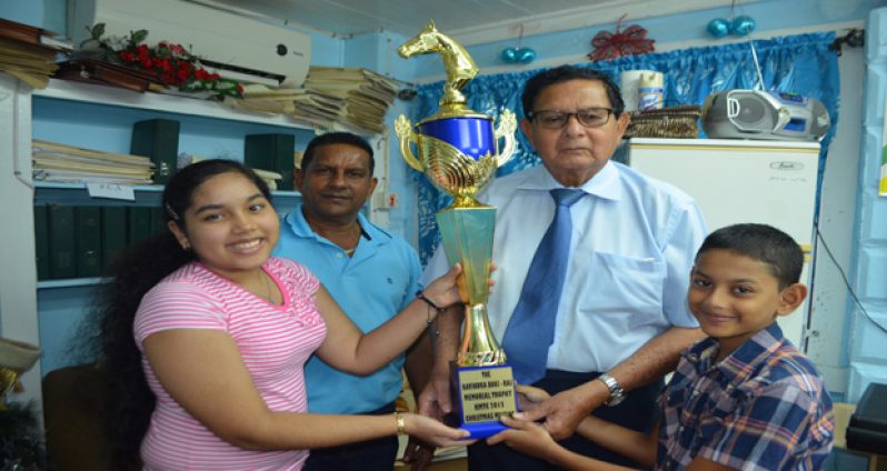 In this Cullen Bess-Nelson photo, Justice Kennard (second right) accepts the winning trophy from Sherisa Booj-Raj while the senior Booj-Raj (second left) and his son Ravindra look on.