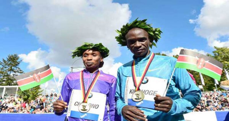 Kenya's Eliud Kipchoge (right) and Kenya's Gladys Cherono pose with their medals and wave Kenyan flags after the 42nd Berlin Marathon, yesterday. Kipchoge failed in his bid to set a third straight world record at the Berlin marathon. AFP photo.