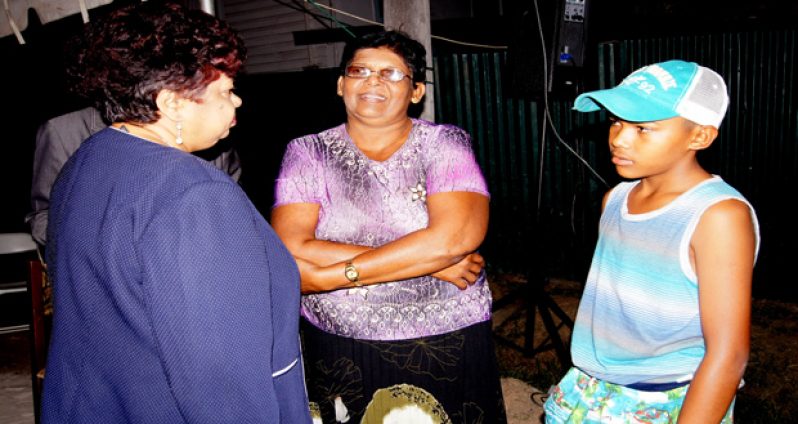Ms. Amna Ally offers comforting words to two survivors of the massacre, Mrs. Gomattie Thomas and her son Roberto Thomas, following the inter-faith service