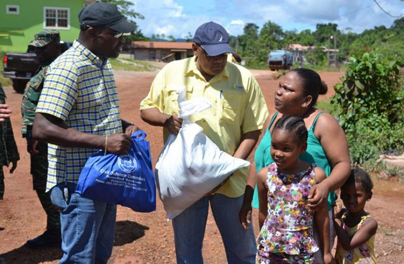 Minister of Public Infrastructure, David Patterson, and Minister of Natural Resources, Raphael Trotman, interact with a family which was affected by the flash floods at Mahdia (DPI photo)