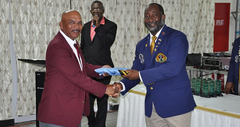 President of the Antigua and Barbuda Shooting Club, Thomas Greenaway (right) hands over the WIFBSC Flag to GuyanaNRA Captain Mahendra Persaud .