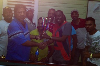 Sponsor Manniram Shew (left) of Shew’s General Store hands over the winning trophy to Colin Hicken while other team members look on.