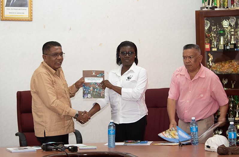 Agriculture Minister Zulfikar Mustapha receiving one of the manuals from WWF representative, Aiesha Williams, in the presence of Chief Fisheries Officer, Denzil Roberts (Shaniece Bamfield photo)