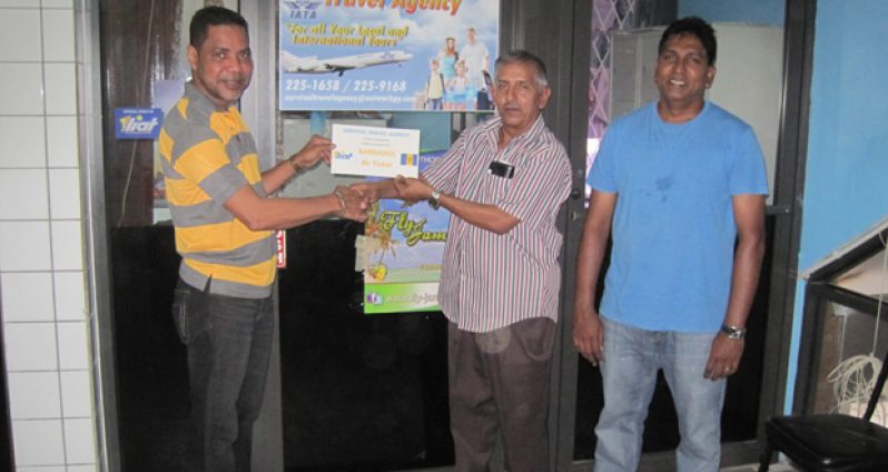 Mark DeFreitas, manager of Survival Travel Agency, hands over Barbados tickets to GFSCA president Ramchand Ragbeer and member Surendra Nauth.