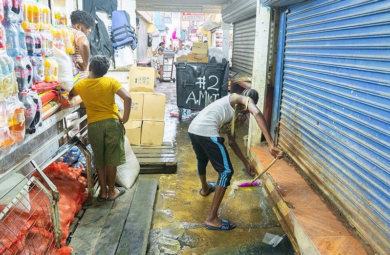 Vendors attempting to get rid of dirty water blocking their businesses (Delano Williams photos)