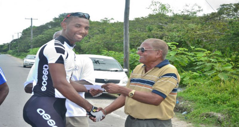 Marlon `Fishy’ Williams (left) accepts his trophy and cash prize from race organiser Hassan Mohamed after winning the R&R International-sponsored 40-mile cycle road race on Sunday. (Photo by Samuel Maughn)