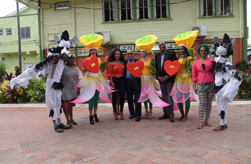 Minister of State, Joseph Harmon (fourth from right) and Minister of Social Cohesion with  responsibility for Culture, Youth and Sport, Dr George Norton (sixth from right) along with the models displaying the revellers’ costumes for the Ministry of the Presidency’s Mash band.