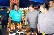 Senior Finance Minister Dr Ashni Singh interacting with a local manufacturer on the first night of Essequibo’s Agro and Trade Fair