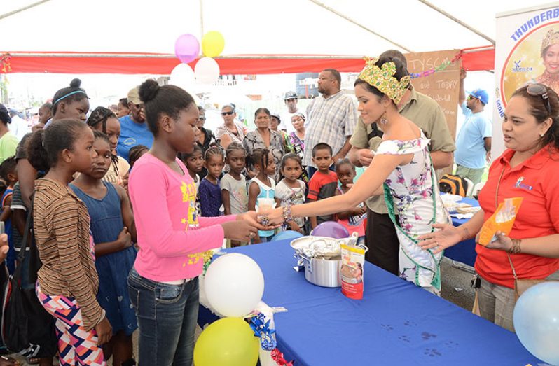 Miss World Guyana Vena Mookram, handing out exercise books with RHTYSC Vice-President Mark Papannah