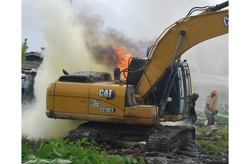 The demolition excavator on fire after being assailed by Molotov cocktails (Elvin Croker photo)