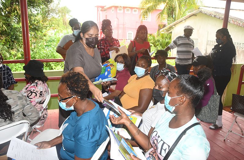 Assistant Director of the Childcare and Protection Agency (CPA), Levine Gouveia, handing out child-safety books to residen