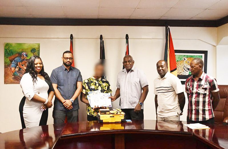 Minister Benn (third from right) presenting the toolkit to the young beneficiary (blurred) at the Ministry of Home Affairs
