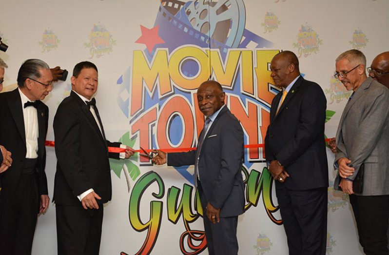 Minister of Foreign Affairs, Carl Greenidge who is currently performing the functions of Prime Minister, cuts the ribbon to mark the official opening of MovieTowne Guyana with MovieTowne's Chairman, Dereck Chin. Also in photo are: Minister of State, Joseph Harmon, Minister of Business and Dominic Gaskin along with other officials