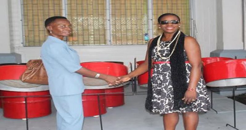 Minister Henry presents the steelpans to Ms. Helligar of the Berbice High School