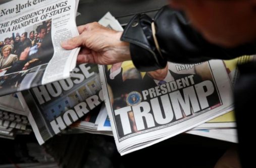 A man hands a newspaper to a customer at a news stand in New York, U.S., November 9, 2016. REUTERS/Shannon Stapleton