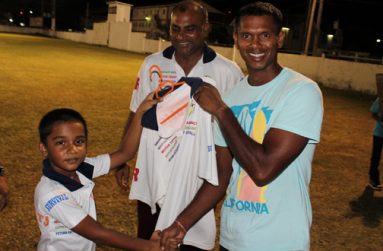 Newest Floodlight player Shivnarine Chanderpaul receives his team shirt from the youngest Floodlight player eight-year old Romeo Deonarain.  Looking on approvingly is Romeo’s father Ricky Deonarain.