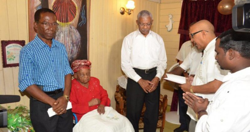 President David Granger with Olive Blackmore as her relatives and members of her church say a prayer