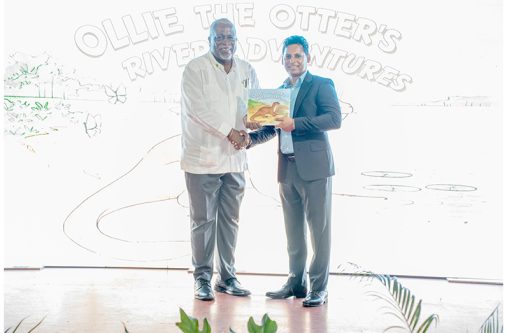 Prime Minister Brigadier (Ret’d) Mark Phillips receives a copy of ‘Ollie the Otter’s River Adventures’ from EMC’s Founder and Director, Shyam Nokta (OPM photo)