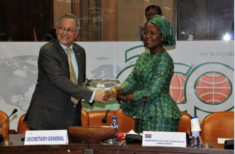 Outgoing Secretary-General  (SG)  Dr Patrick Ignatius Gomes (left), accepts a symbolic gift from  Chair of the Committee of Ambassadors, Teneng Mba Jaiteh (right).