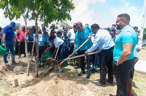 Chairman of the PAC Board of Directors, Robert Persaud, flanked by students, and other officials during the tree planting ceremony (Japheth Savory Photo)