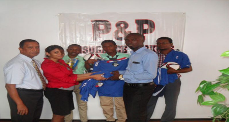 Melinda Sammy, accounts executive of P&P Insurance hands over some of the uniforms to Leon Bishop in the presence of Bish Panday and other representatives of the school.