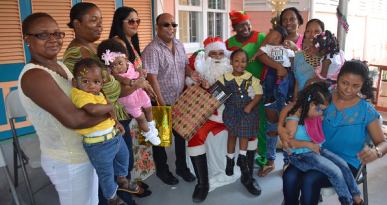 Comfort Sleep’s Managing Director Dennis Charran and wife Sabita, third and fourth from right, share a photo moment with Santa as he distributes toys to the kids (Cullen Bess-Nelson photo)